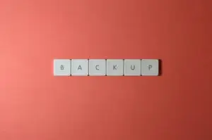 Free Close-up of keyboard keys spelling 'BACKUP' placed on a coral-colored surface. Stock Photo