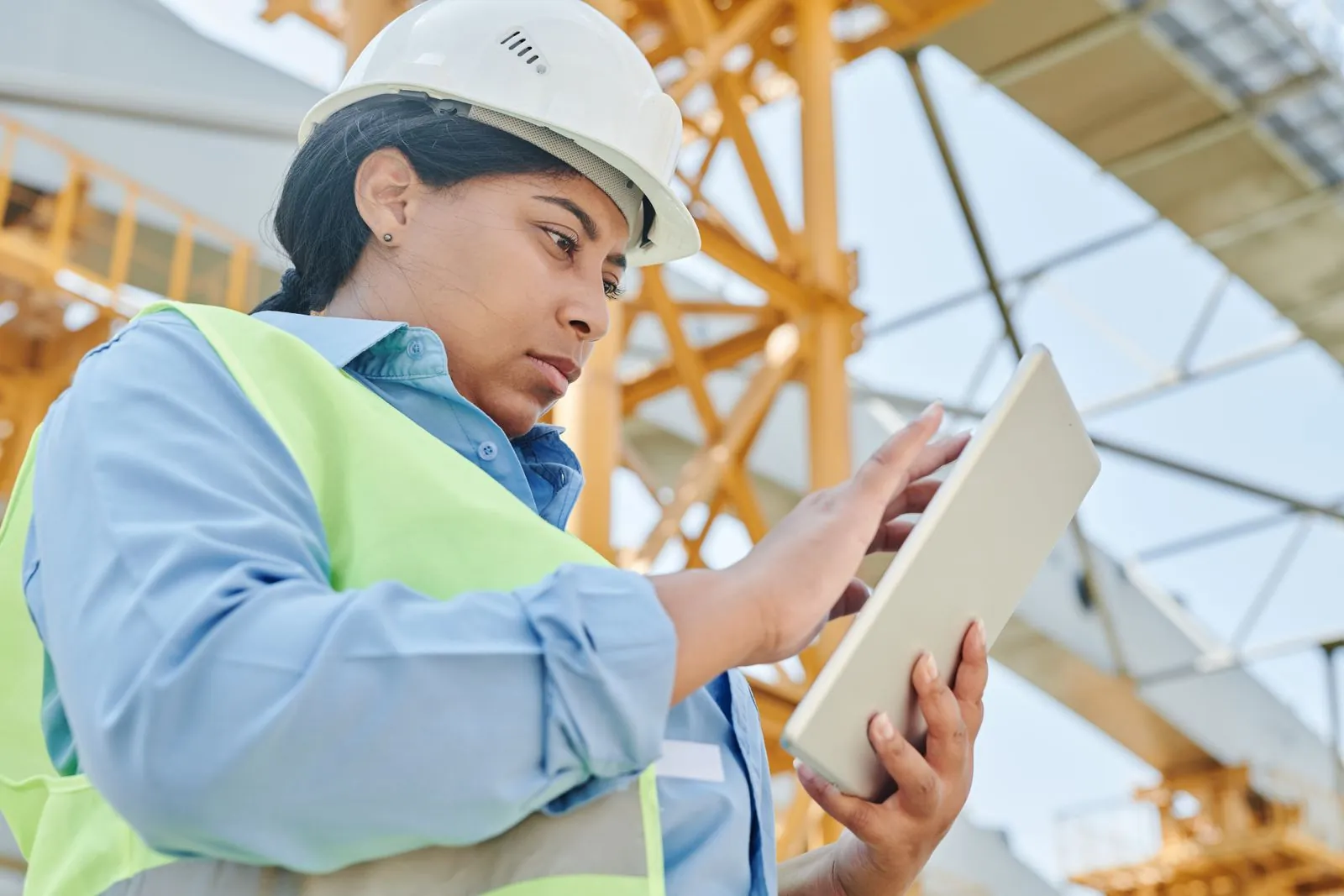 Engineer in a hard hat checking a tablet at a construction site