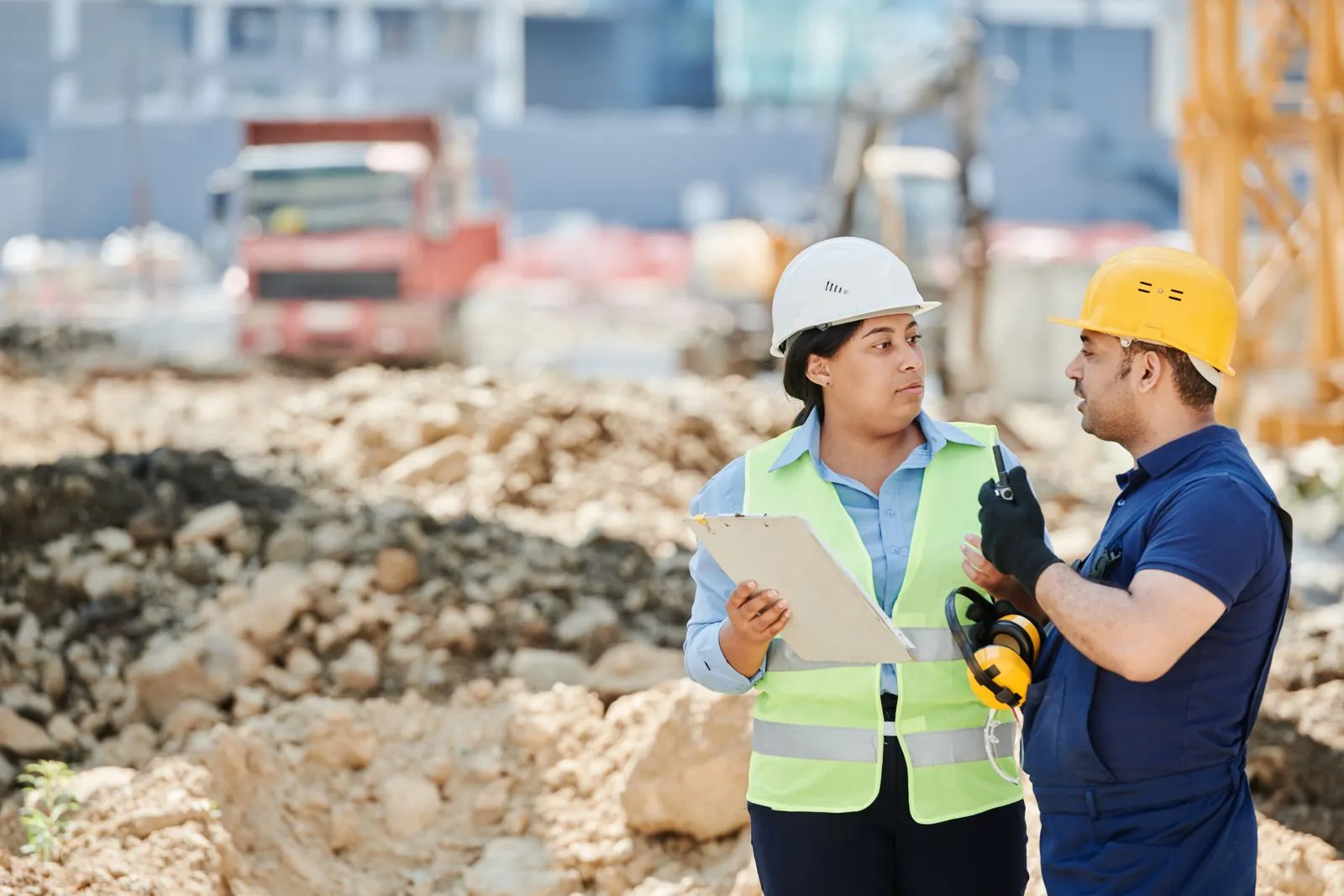 Two construction workers in hard hats talking on a job site